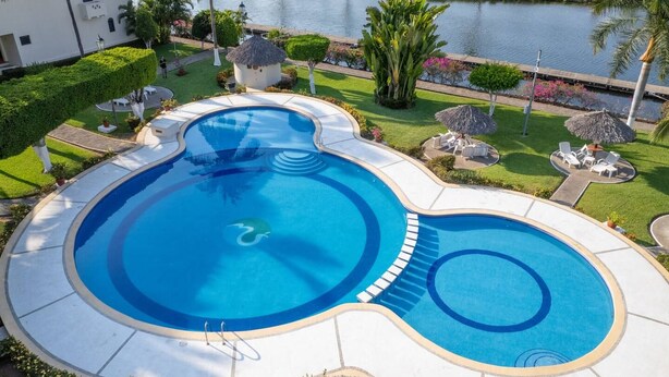 Une piscine au design original, entourée d’un aménagement paysager soigné et offrant une vue sur une étendue d’eau.