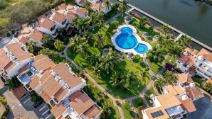 Un quartier résidentiel comprenant plusieurs maisons, une piscine et un plan d’eau.