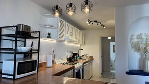 A modern kitchen with a built-in microwave, gas stove, and hanging pendant lights. - Luxury Condo Overlooking Marina in Ixtapa (Ixtapa)