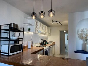 A modern kitchen with a built-in microwave, gas stove, and hanging pendant lights. - Luxury Condo Overlooking Marina in Ixtapa (Ixtapa)
