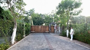 A paved driveway leading to a gated entrance with a wooden fence, surrounded by greenery and a lamp post. - Luxury Condo Overlooking Marina in Ixtapa (Ixtapa)