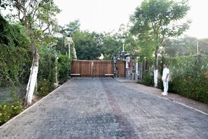 A paved driveway leading to a gated entrance with a wooden fence, surrounded by greenery and a lamp post. - Luxury Condo Overlooking Marina in Ixtapa (Ixtapa)