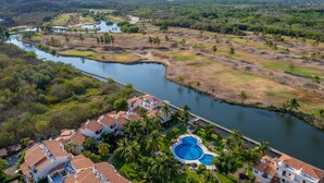 A resort with a swimming pool, a river, and surrounding greenery. - Luxury Condo Overlooking Marina in Ixtapa (Ixtapa)