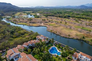 A resort with a swimming pool, a river, and surrounding greenery. - Luxury Condo Overlooking Marina in Ixtapa (Ixtapa)