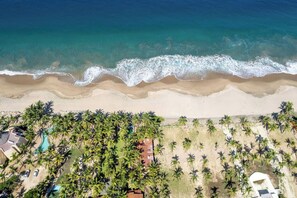 An aerial view of a beach resort with a sandy shoreline, palm trees, and a swimming pool. - Your Private Piece of Mexican Beachfront Luxury (Playa Blanca)