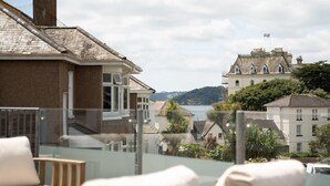 A balcony with a view of a coastal town, including buildings and a body of water.