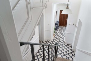 A staircase with a black and white patterned floor, white walls, and a hanging light fixture. - Spacious House nr Castle Beach, Parking & Sauna (Cornwall)