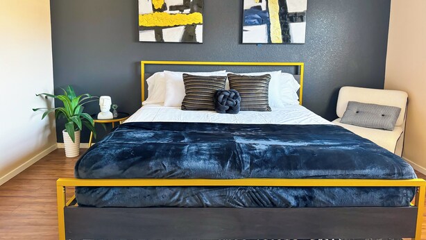 Un dormitorio moderno con una cama, una silla y dos cuadros abstractos en la pared.