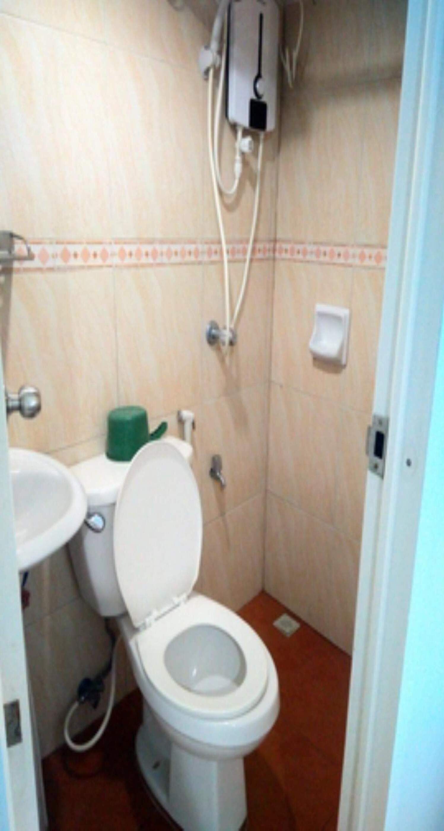 A small bathroom with a toilet, sink, and a wall-mounted electrical outlet.
