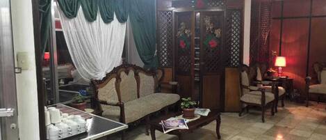 A living room with a sofa, chairs, a coffee table, and a decorative screen.