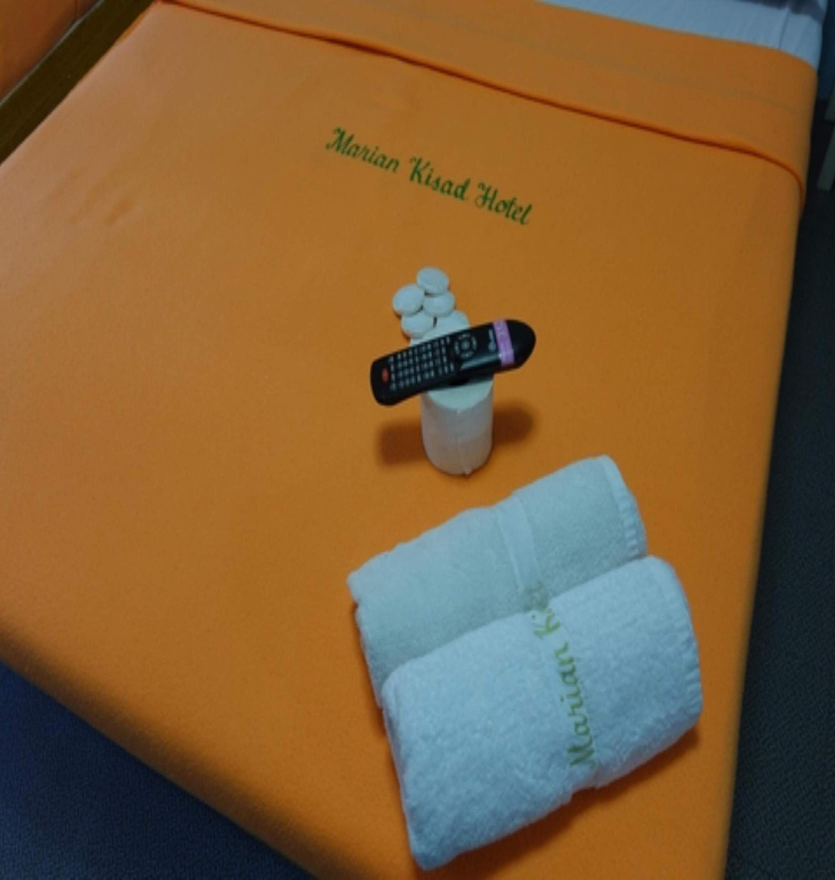 A brochure for Marian Road Hotel with a remote control and a folded towel on top.