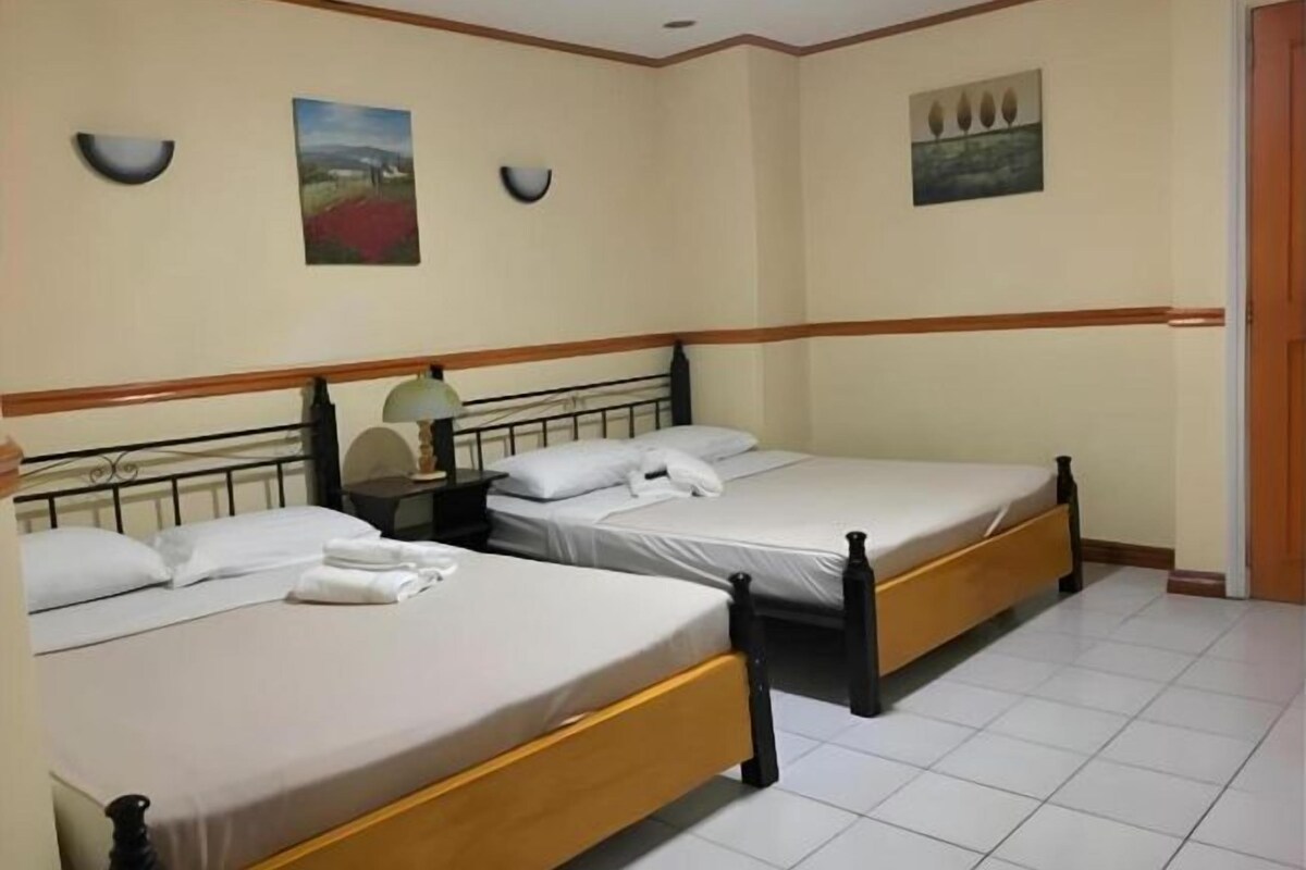 Une chambre d’hôtel avec deux lits simples, une table de chevet avec une lampe et un tableau au mur.