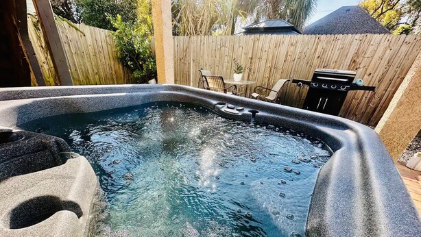 A hot tub with a wooden deck and a barbecue grill in the background. - 1920s Cottage Downtown, Ybor with Hot Tub! (Tampa)