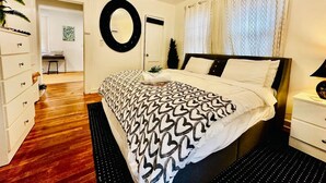 A bedroom with a bed, a dresser, a mirror, and a door leading to another room. - 1920s Cottage Downtown, Ybor with Hot Tub! (Tampa)