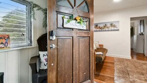 A wooden door with a 'Welcome' sign, a window with blinds, and a painting of palm trees on the wall. - 1920s Cottage Downtown, Ybor with Hot Tub! (Tampa)