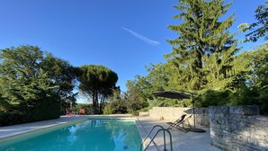 A swimming pool with a stone wall and a tree in the background.