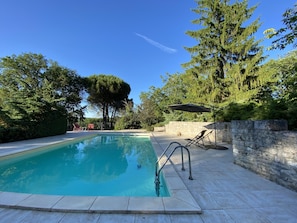 A swimming pool with a stone wall and a tree in the background.