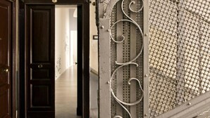 A hallway with a dark wooden door and a metal gate with decorative scrollwork. - Archivio 32 Neapolitan Apartment (Napoli)