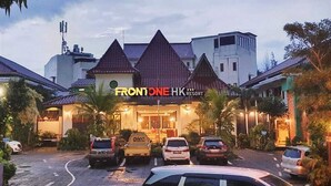 Un hôtel avec une enseigne bien visible portant l’inscription « FRONTONE HK RESORT » et plusieurs voitures garées devant.