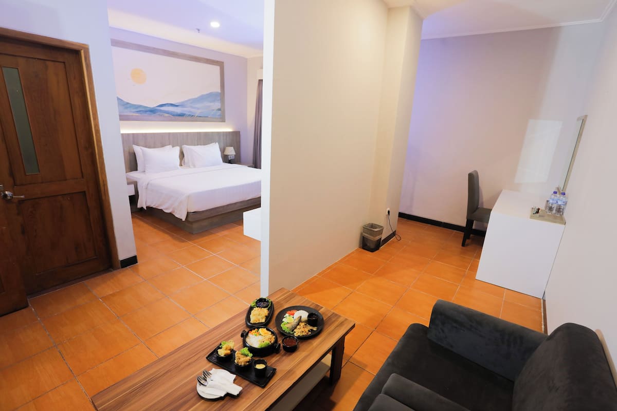 A hotel room with a bed, a dining table with food, a TV, and a bathroom.