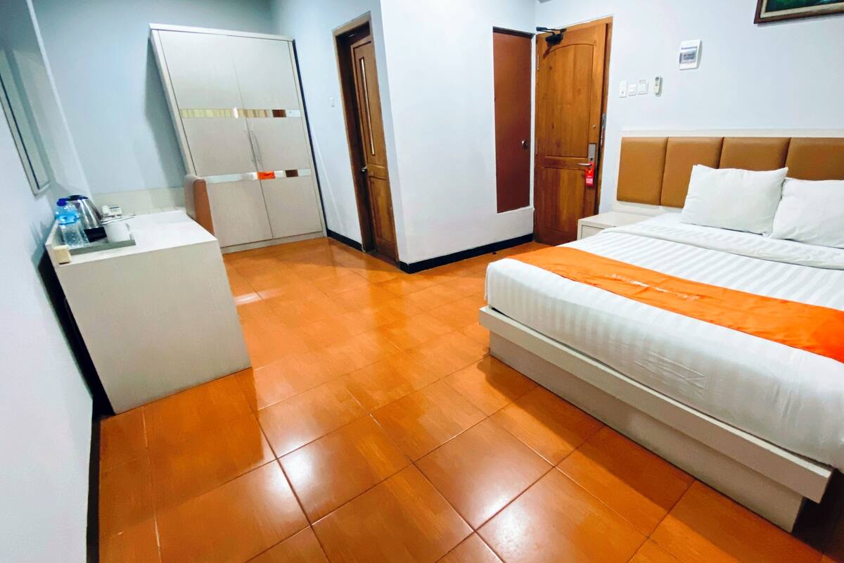 A hotel room with a bed, a desk, and a wardrobe.