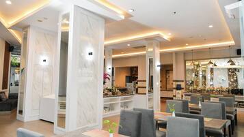 Un ristorante moderno con colonne in marmo, sedie rivestite di grigio e diversi tavoli da pranzo.