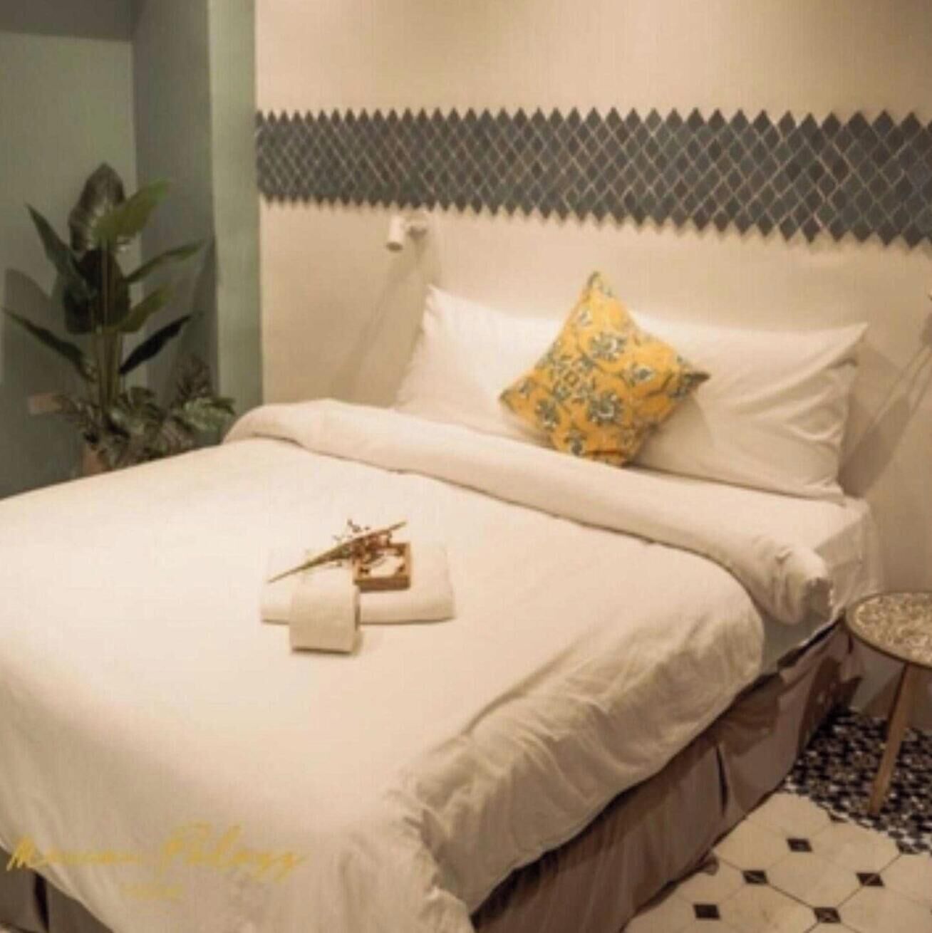A neatly made bed with white linens and a single decorative pillow.