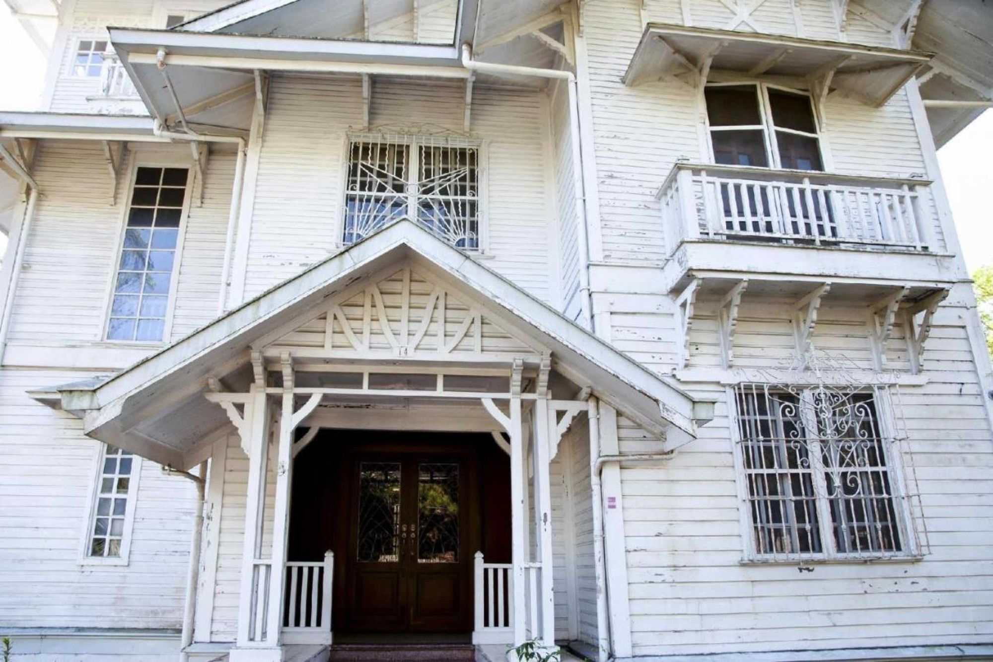 A multi-story building with a central entrance, balconies, and barred windows.