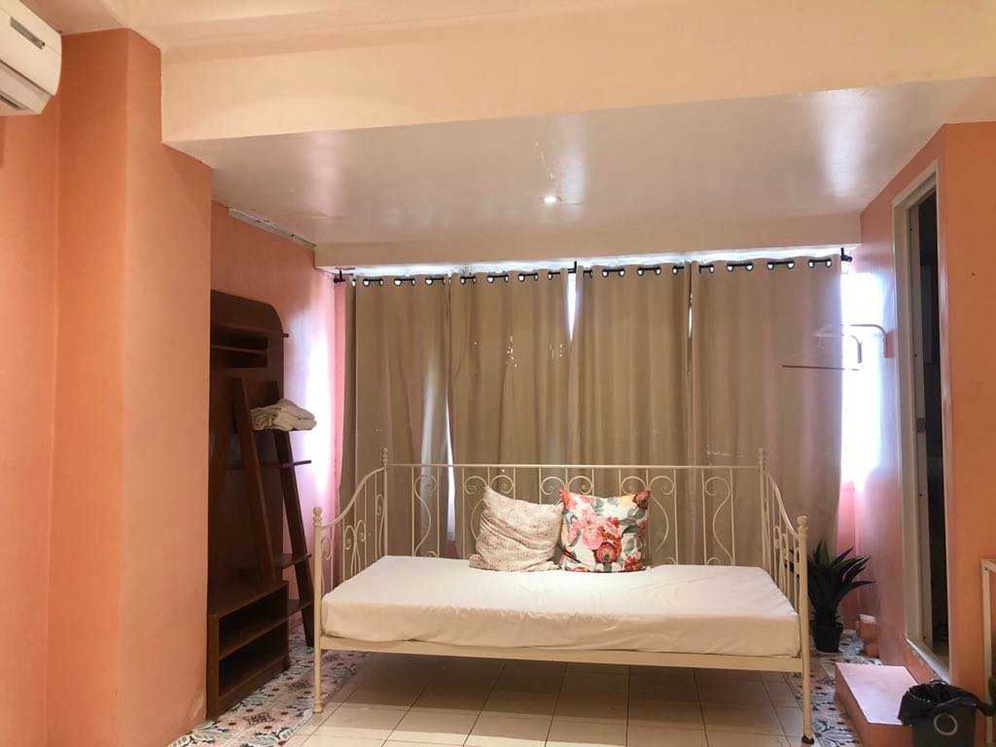 Un lit simple avec un cadre en métal, un rideau et un radiateur.