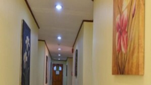 A hallway with cream walls, a tiled floor, and a wooden door at the end. - Marian Palazz Hotel (Baguio)