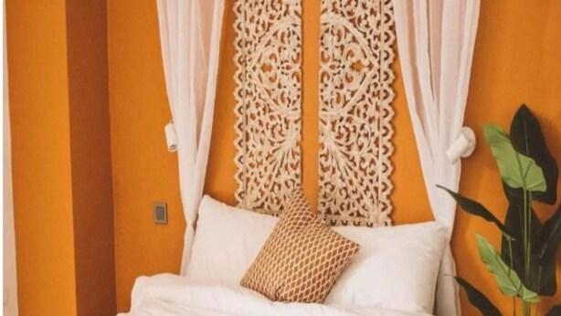A neatly made bed with white linens, a patterned pillow, and a bedside table with a book and a tissue box. - Marian Palazz Hotel (Baguio)