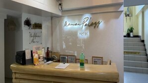 A reception desk at Manana Palazzetto Hotel with a modern design, a chandelier, and a staircase in the background. - Marian Palazz Hotel (Baguio)