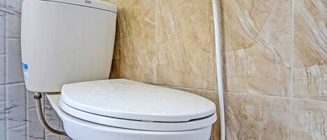 A toilet with a marble wall and a patterned floor.