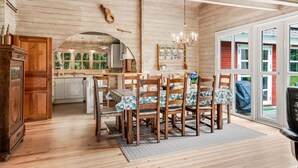 Un intérieur en bois comprenant un coin repas, une cuisine et de grandes fenêtres.