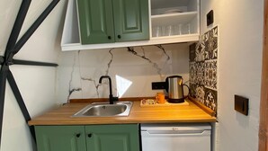 A compact kitchen with green cabinets, a white dishwasher, a marble backsplash, and a geometric ceiling design. - EVALAND GLAMPING RESORT (Ardesen)