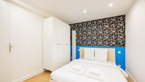A bedroom with a bed, white curtains, a wardrobe, and a patterned wall. - Appart 8pers # 3 Bedrooms # Pereire # Paris 17 (Paris)