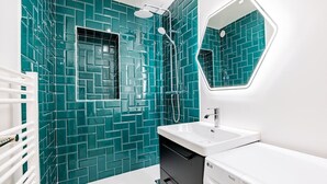 A bathroom with teal mosaic tiles, a white sink, a mirror, and a washing machine. - Appart 8pers # 3 Bedrooms # Pereire # Paris 17 (Paris)