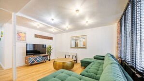 A modern living room with a green sofa, a round coffee table, and a flat-screen TV. - Appart 8pers # 3 Bedrooms # Pereire # Paris 17 (Paris)