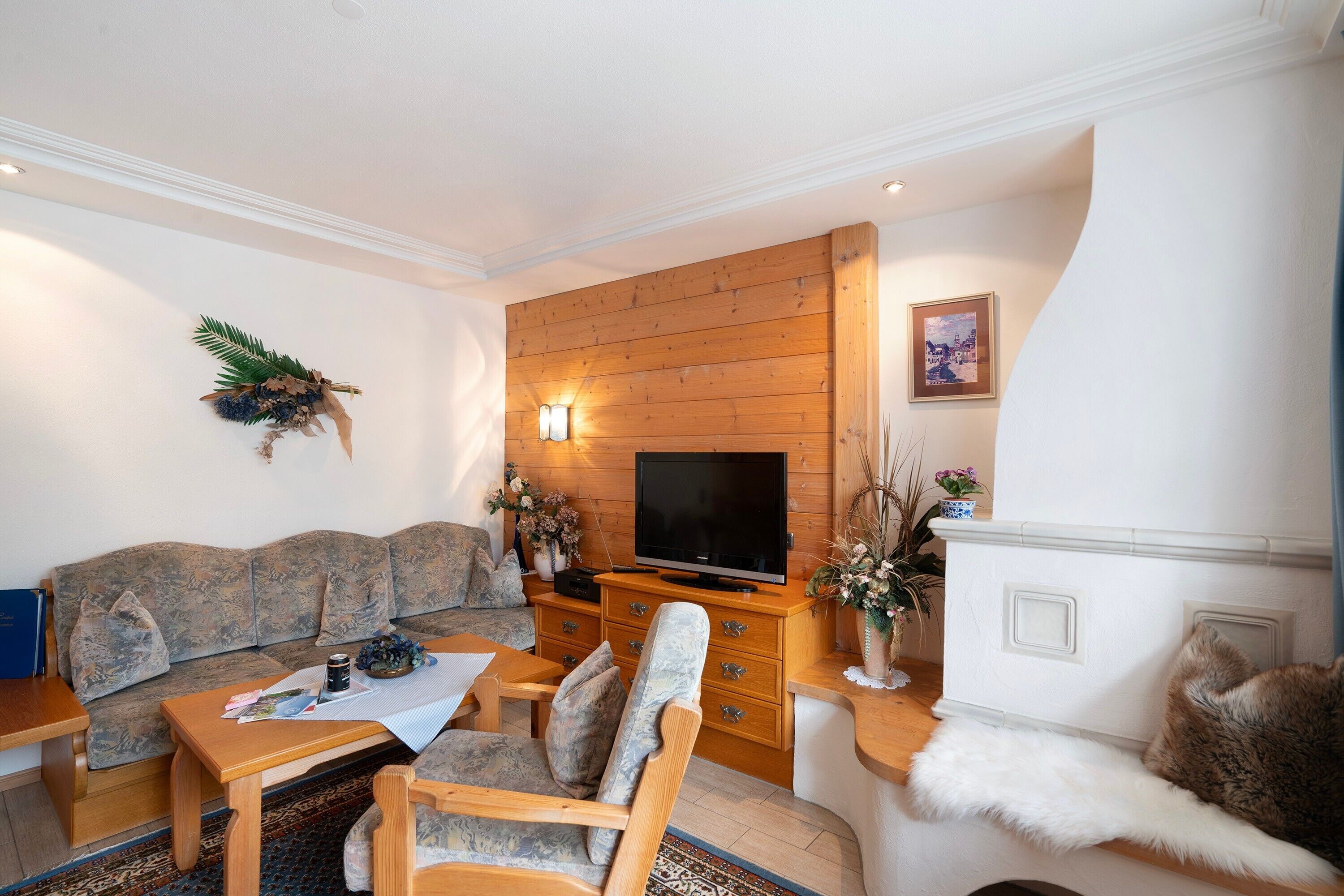 A living room with a sofa, a wooden coffee table, a TV on a wooden stand, and a fireplace.
