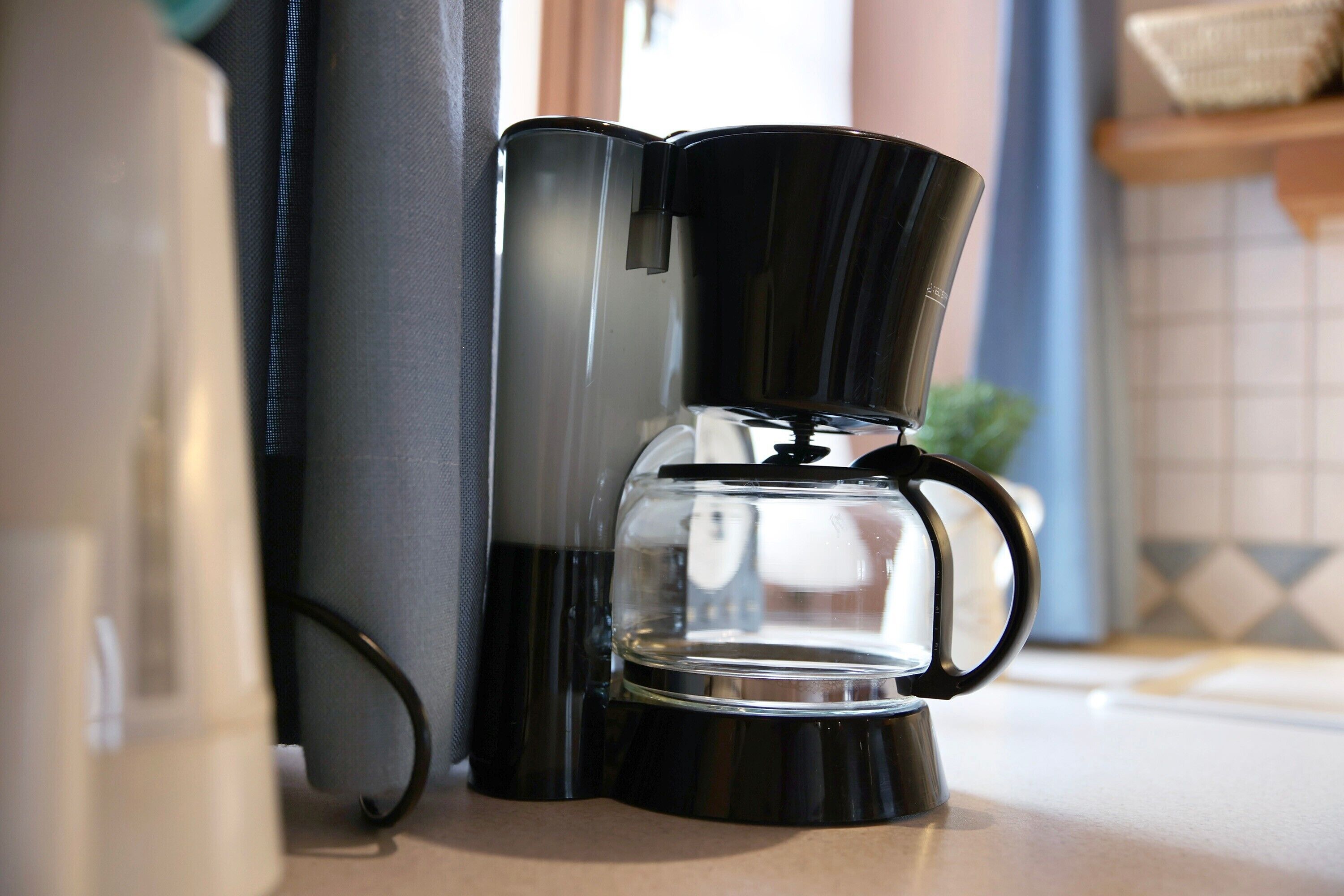 En kaffebryggare med en genomskinlig kanna stående på en köksbänk.