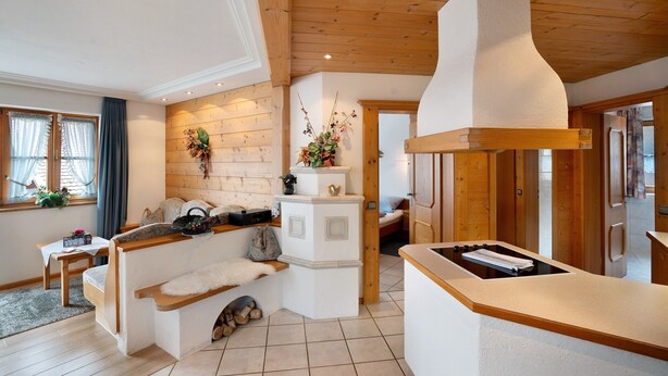 Una cucina accogliente con travi in legno, un piano cottura integrato e un angolo conversazione con una panca e un tavolo.