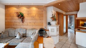 Un interno moderno con una parete in legno, un divano con cuscini, un tappeto bianco e un angolo cottura con lavello e piano di lavoro.