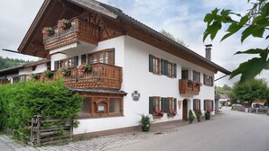 Tipico chalet con balconi in legno, fioriere e strada acciottolata.