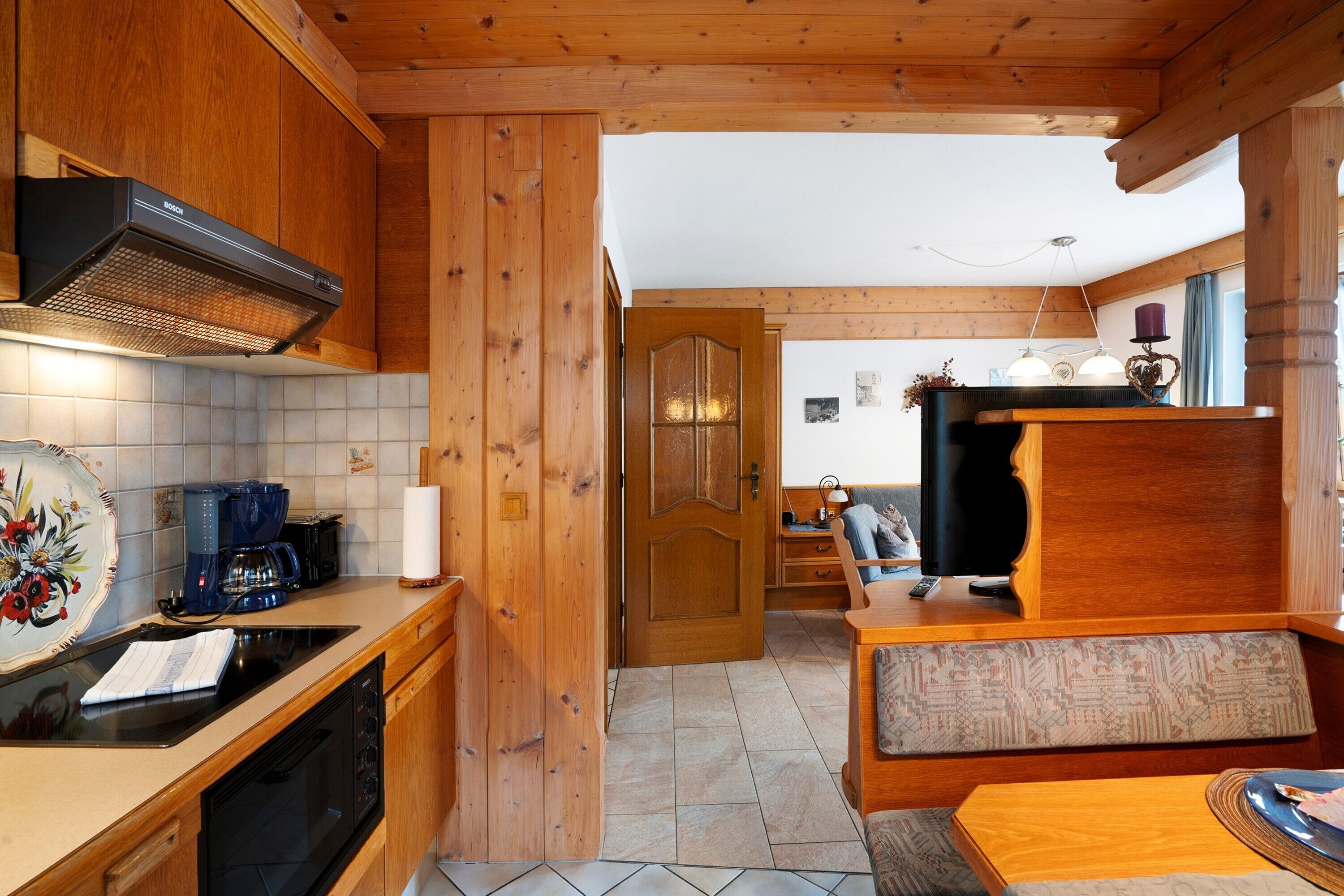 A wooden interior with a kitchen area, a dining table, and a bench.