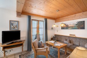 A living room with a TV, wooden furniture, a sofa, a table, and a painting on the wall.