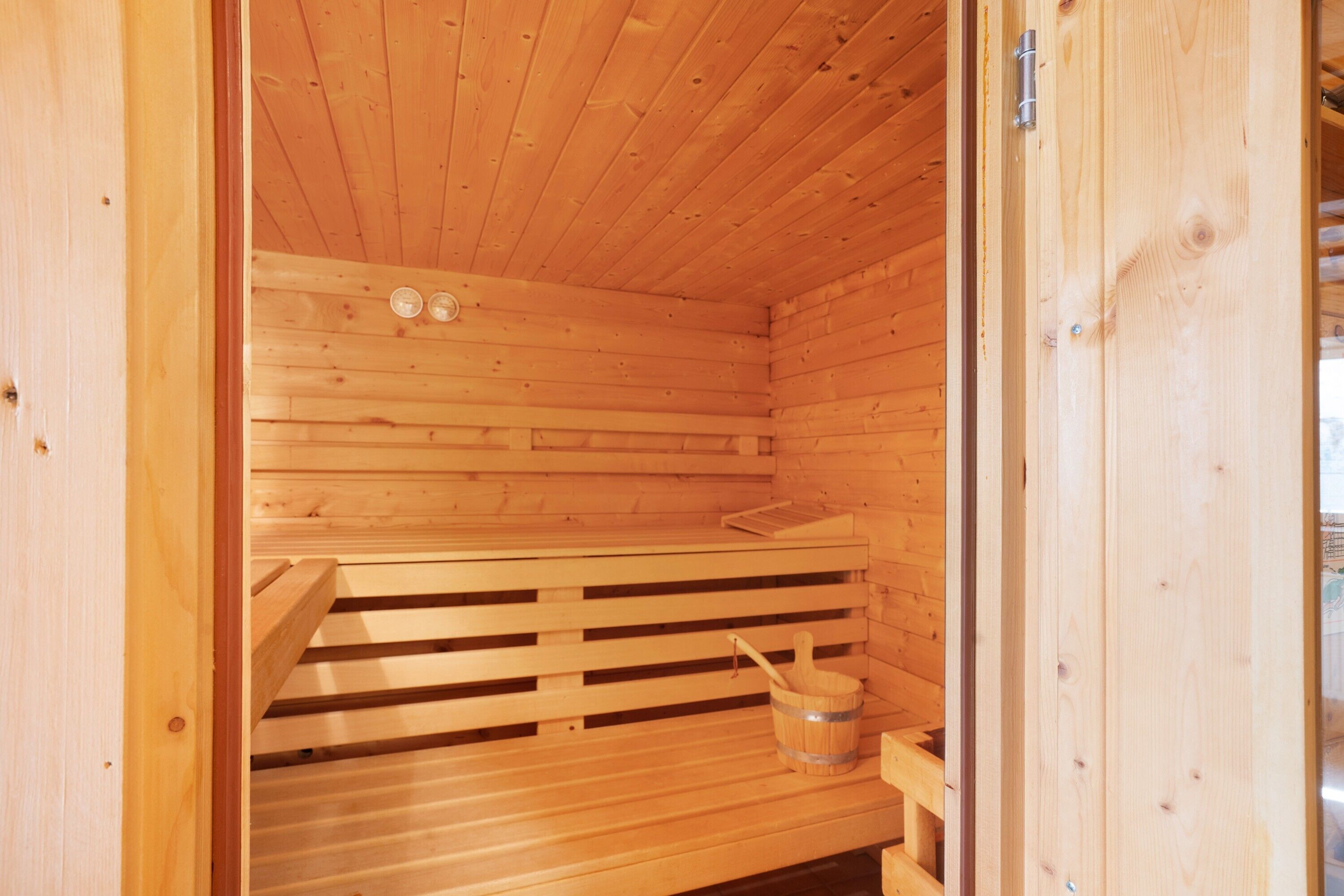 A wooden sauna with benches and a bucket.