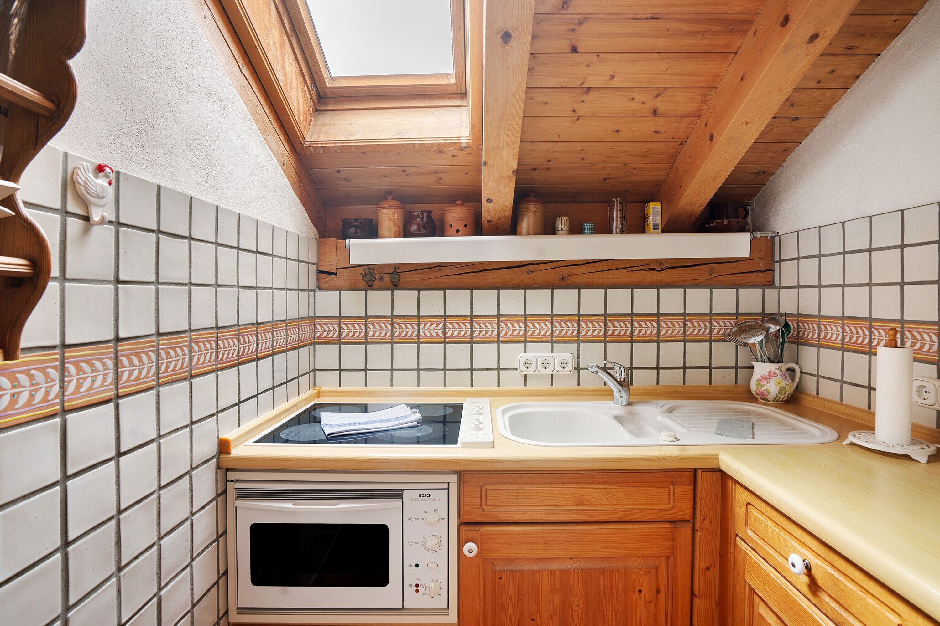 A kitchen with a Bosch oven, a sink, a window, and wooden cabinets.
