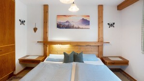 Une chambre à coucher comprenant un lit, une tête de lit en bois, deux tables de chevet, un tableau accroché au mur et des décorations murales en forme de papillons.
