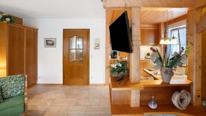 Un intérieur en bois avec un téléviseur fixé au mur, une porte en bois et une chaise verte.