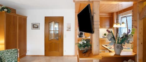A wooden interior with a TV mounted on a wall, a wooden door, and a green chair.